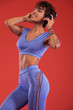 © Mike Orlov - Fitness and sport motivation.. Strong and fit athletic, woman with tattoo posing on red background in sportswear.