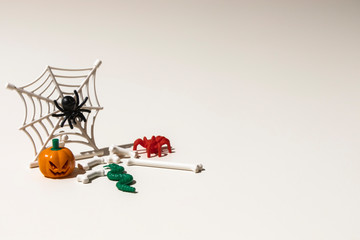 Composition of plastic toys for Halloween, with pumpkin, spider, cobweb, snake and bones