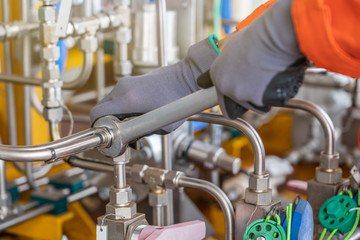 A mechanic operator fix and tighten stainless steel tubing system by using combination wrench, offshore oil and gas industry maintenance and service business.