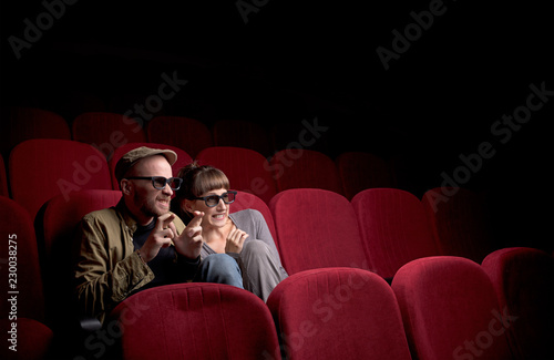 Fotografija Young cute couple sitting alone at red movie theatre and having fun
