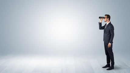 Wall Mural - businessman looking forward with binoculars in an empty space