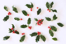 Christmas Holly With Red Berries. Traditional Festive Decoration. Holly Branch With Red Berries On White Table Background. Flat Lay, Top View.