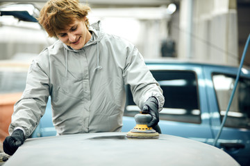 Wall Mural - mechanic worker repairman sanding polishing car and preparing automobile for painting