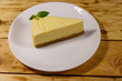 © olyasolod - Piece of tasty sweet New York cheesecake in a white plate on wooden table