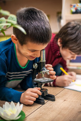 closeup portrait of little boy using microscope on biology lesson
