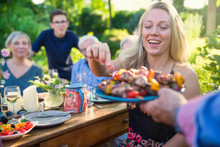 Cheerful Family Gathered Around A Table For A Bbq In The Garden