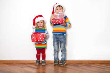 Happy children in Santa red hats holding Christmas presents on a white background. Christmas time.
