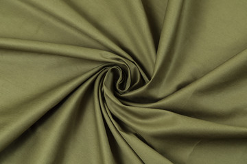 The monophonic matter of green olive color showing a beautiful drapery folds in the form of a spiral