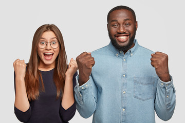 Mixed race woman and man triumph and feel happiness after winning first place, clench fists, cheer good news, have broad smiles, isolated over white background. Body language and success concept