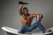 © Volodymyr - Wine festival concept. Champagne or wine celebration. Handsome brutal man pouring champagne in the bath on gray background.