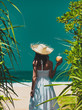 © Masson - Young woman in a hat with coconut cocktail near the sea