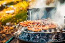 BBQ With Fiery Sausages On The Grill Outdoor Picnic. Spending Time Together With The Family At The Grill. Social Meetings, Friends. Juicy And Well-grilled Sausages