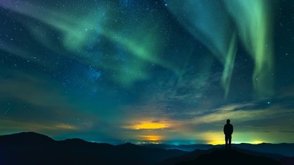 Wall Mural - The man standing on the mountain on the northern light background. time lapse
