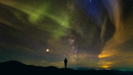 Wall Mural - The man standing on a background of the city with a northern light. time lapse