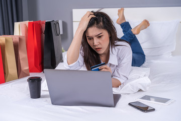 Sticker - stressed woman using laptop for online shopping on bed, and having problem with blocked credit card