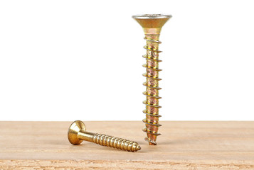 Poster - Two golden screws on wooden plank, white background