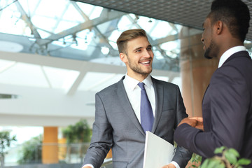 Two multinational young businessmen discussing business at meeting in office.