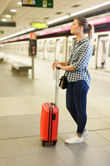  Girl standing with suitcase on metro platform