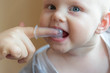© Pavlo - Mom brushes baby's teeth with a brush that fits on her finger