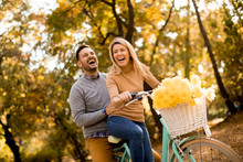 Active Young Couple Enjoying Riding Bicycle In Golden Autumn Park