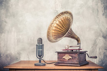 Vintage Antique Gramophone Phonograph Turntable With Brass Horn And Big Aged Studio Microphone On Wooden Table Front Concrete Wall Background. Retro Old Style Filtered Photo