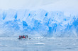 Snowfall over boat with tourists in the bay full of icebergs with huge glacier wall in the background, near Almirante Brown, Antarctic peninsula
