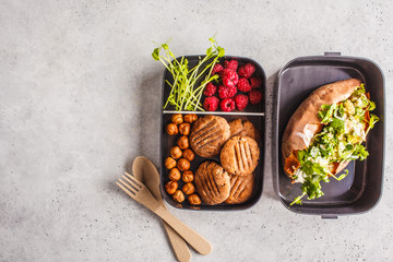 Healthy meal prep containers with quinoa Stuffed Sweet Potatoes, cookies and berries, overhead shot with copy space.