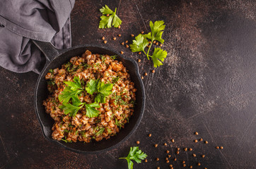 Buckwheat with meat in a cast iron pan on a dark background, copy space, top view,