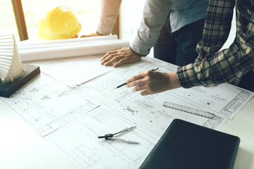 Two engineering man standing examining working on blueprint.