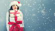 © Tierney - Young woman with santa hat holding gift boxes on a gray background