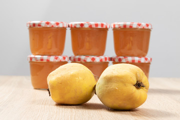 Wall Mural - Two ripe quinces in front of some glasses of quinces jam 