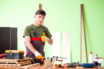 Wall Mural - Young man carpenter working in workshop 