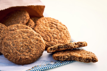 Homemade shortbread cookies made of oatmeal are stacked on cloth and paper bag on white table background. Concept food healthy snack for enjoy in holiday. With copy space for text.