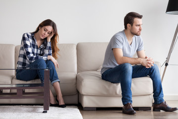 Sad, desperate, frustrated young couple no desire to talk after quarrel. Man sitting with back to wife, thinking of relationship problems. Troubles in family, misunderstanding, distrust