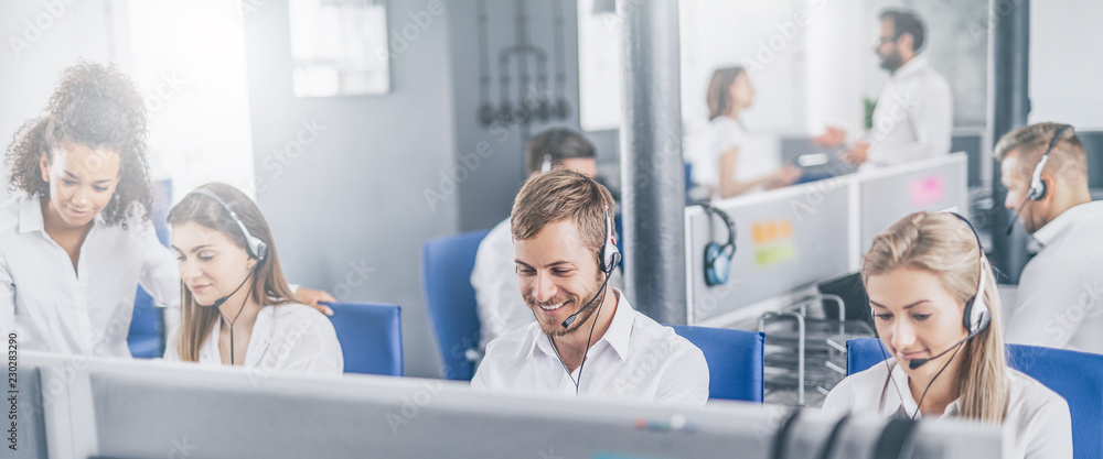 Call center worker accompanied by his team. - obrazy, fototapety, plakaty 