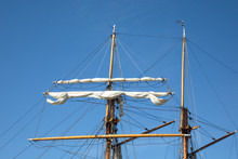 The Furled Sails And Rigging Of A 3-masted Schooner, Seen Against The Backdrop Of A Bright Blue Cloudless Morning Sky, While Moored At An Inlet In Kökar, Åland Islands, Finland.