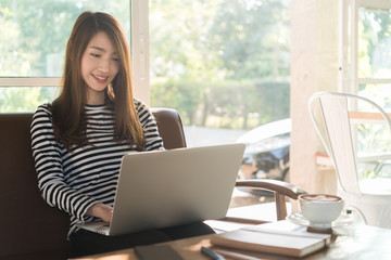 Beautiful young teenage woman freelance work with laptop at coffee shop in with sun light, freelance lifestyle conceptual