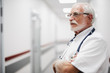 © Yakobchuk Olena - Side view portrait of bearded gentleman in white lab coat crossing arms and looking away with serious expression, Copy space on left side