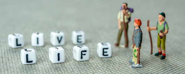 Wall Mural - live life white cubes on grey background with miniature figurines