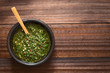 Raw homemade Argentinian green Chimichurri salsa or sauce made of parsley, garlic, oregano, hot pepper, olive oil, vinegar, photographed overhead with natural light (Selective Focus on the salsa)