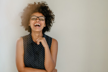 Laughing young woman standing by a wall