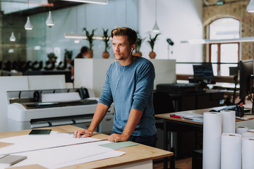 Serious handsome male engineer listening to music while making a blueprint