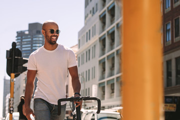 Handsome man enjoying city walk with a bicycle