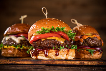 Tasty burgers on wooden table.