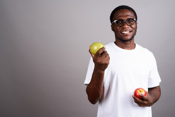 Young African man wearing white shirt and eyeglasses against gra