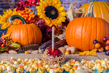 Popcorn Peanuts Candy Corn And Red Candy Apple On Blue Table With Background Of Fall Flowers Berries Nuts Autumn Leaves Yellow Sunflowers And Orange Pumpkins On Burlap