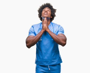 Poster - Afro american surgeon doctor man over isolated background begging and praying with hands together with hope expression on face very emotional and worried. Asking for forgiveness. Religion concept.