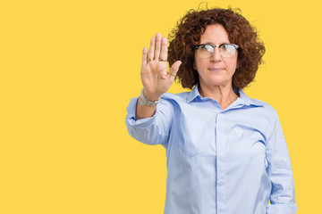 Beautiful middle ager senior businees woman wearing glasses over isolated background doing stop sing with palm of the hand. Warning expression with negative and serious gesture on the face.