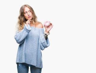 Poster - Beautiful young blonde woman eating pink donut over isolated background serious face thinking about question, very confused idea