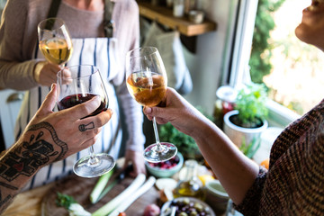 Friends having white wine while cooking in a kitchen